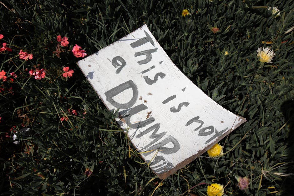 A weathered white wooden sign with black handwritten text that reads 