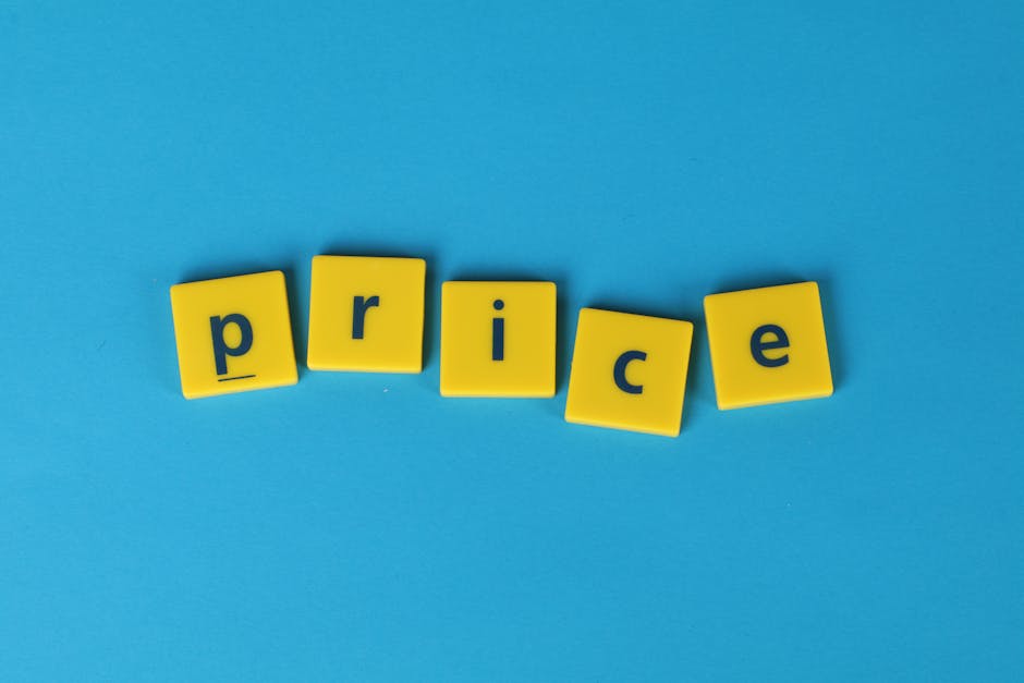 Six yellow letter blocks with black lowercase letters spelling the word 'price' are arranged on a smooth, solid light blue surface. The blocks are slightly tilted and spaced evenly, with the letters facing upwards and centered in the image. The background is plain, with no additional objects or context visible, providing a clean and simple visual focus on the spelling of the word. This arrangement could subtly relate to the topic of cost or expense, relevant to rubbish removal services or pricing discussions in waste management. The lighting is even, with no harsh shadows or reflections, highlighting the textures and vibrant colors of the blocks against the contrasting background.